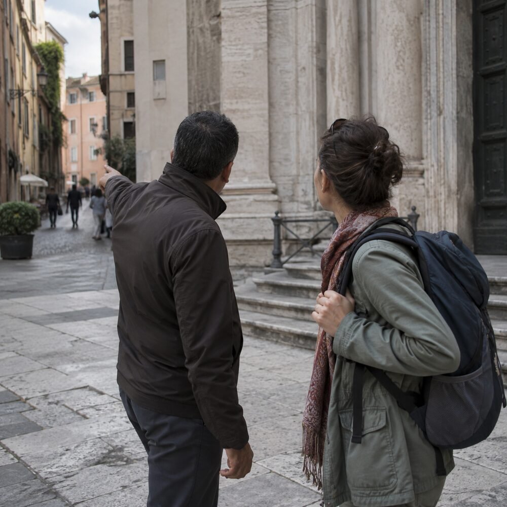 A tourist being redirected away from a monument entrance by a man gesturing down a side street