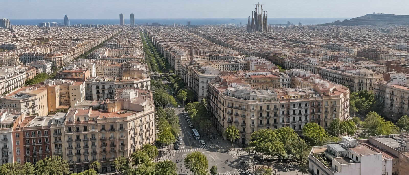 A wide daytime view of Barcelona's Eixample grid from above, ordinary city life, no drama