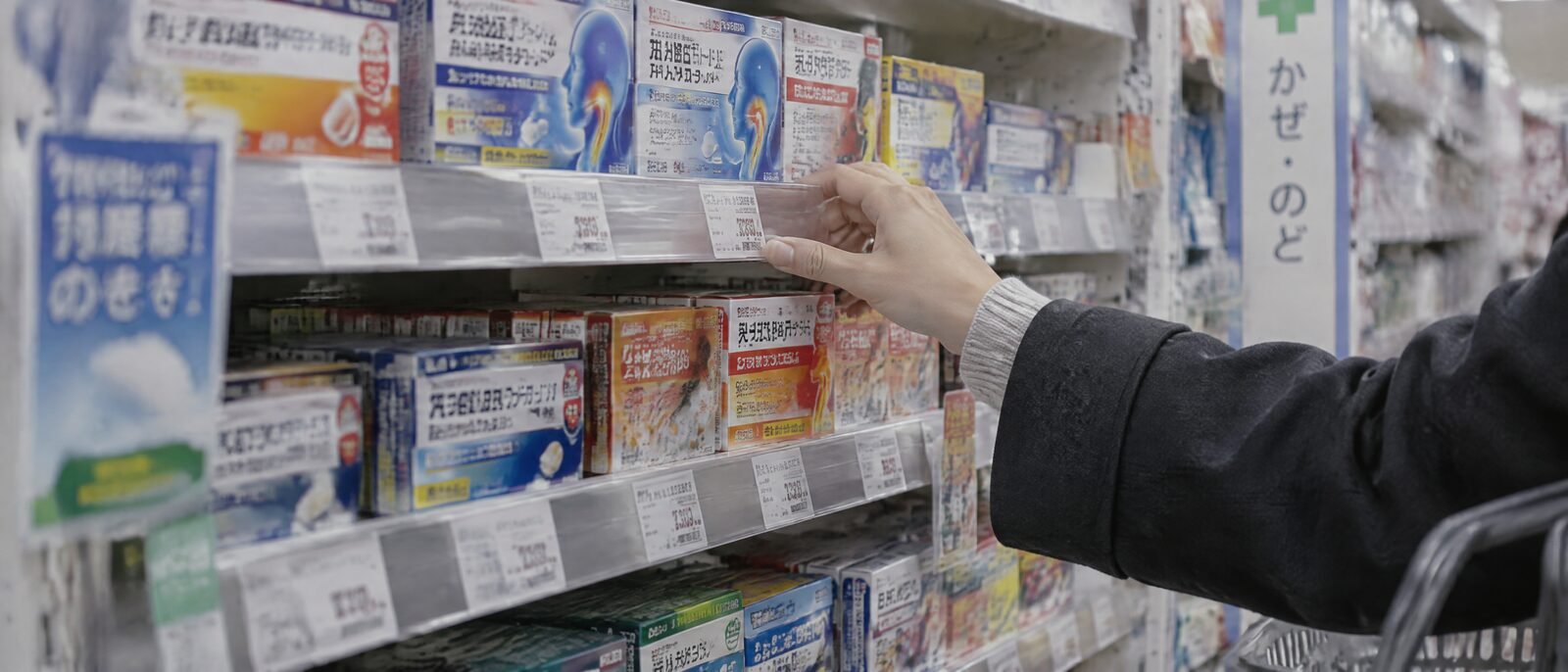 A pharmacy shelf of over-the-counter cold medicine packaging in Japanese
