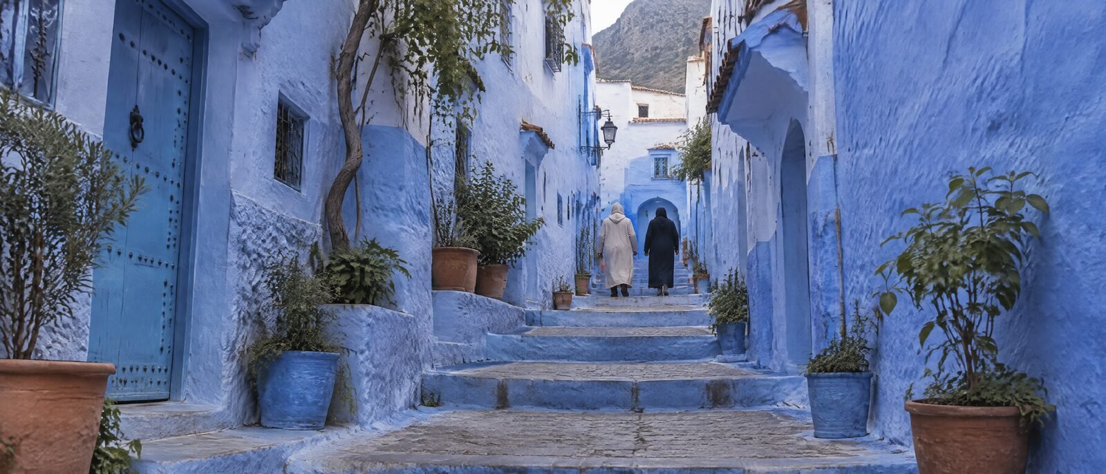 The blue-painted streets and stairways of Chefchaouen, Morocco, in soft daylight, a few pedestrians